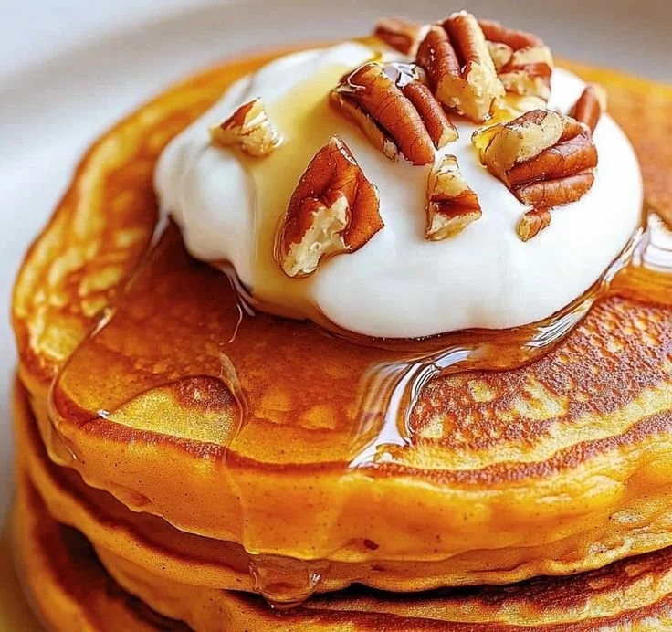 Fluffy sweet potato pancakes stacked with syrup on a plate